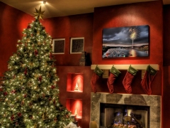 Verlichte kerstboom naast de open haard waar sokken boven hangen