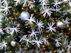 Kerstboom met kerstlichtjes, witte kerstbloemen en kerstballen